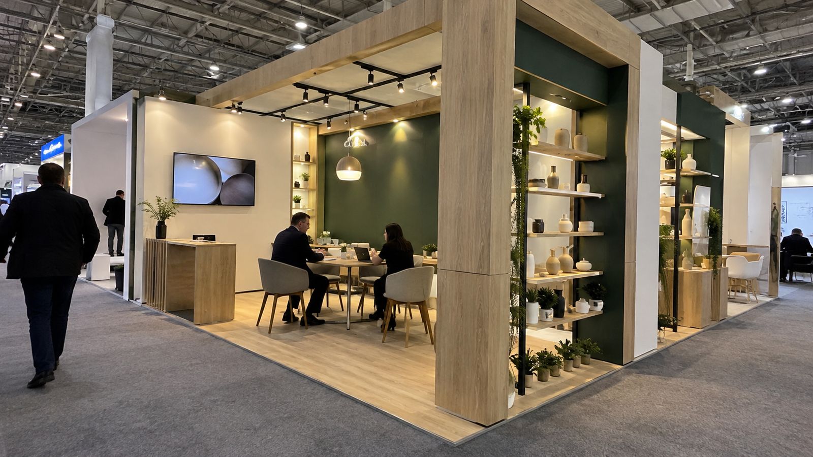 A custom exhibition stand with timber-look panels, product shelves and a meeting area.