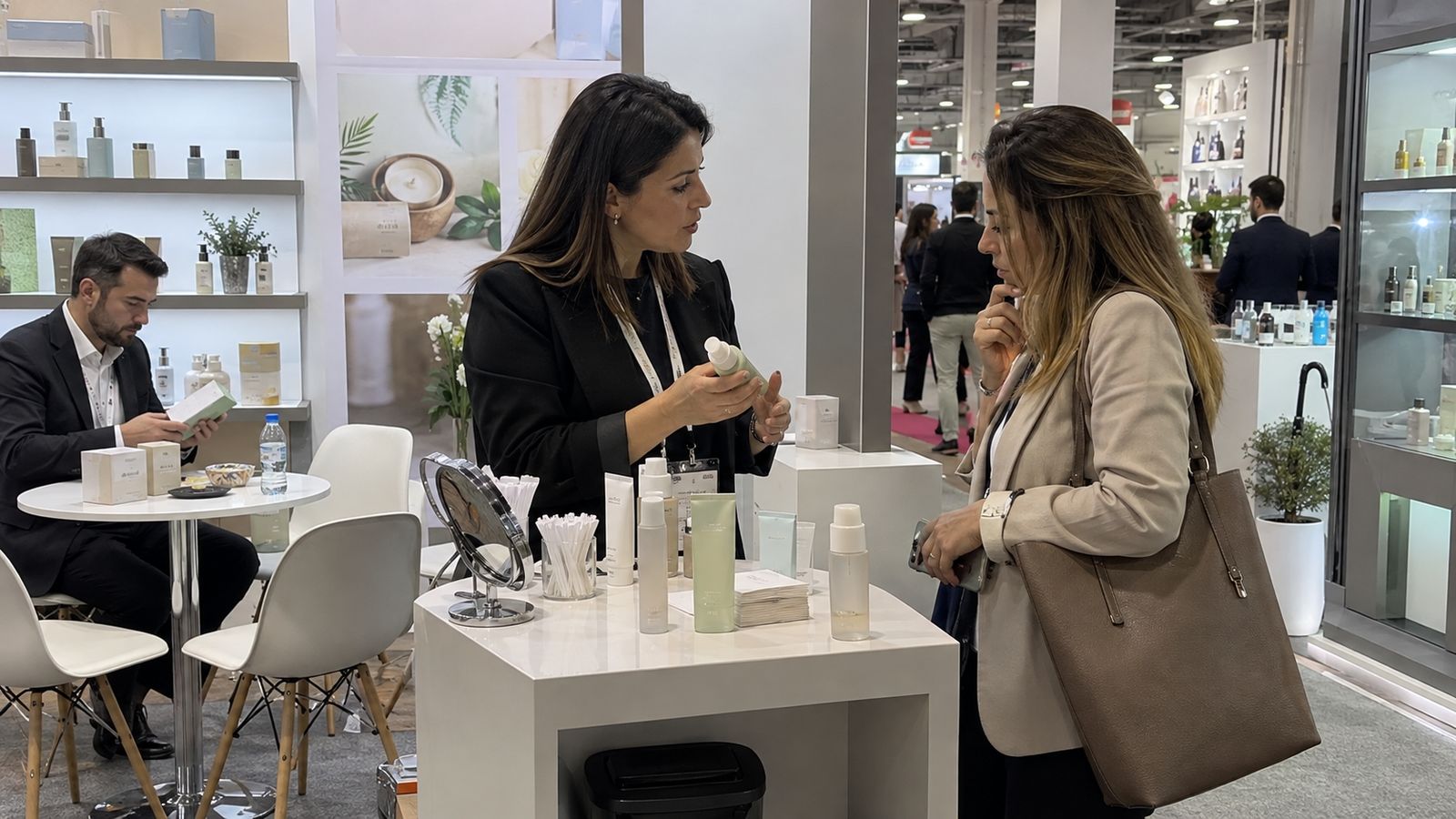 A product discussion at a cosmetics exhibition with skincare displays and a tester counter