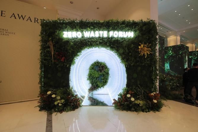 Illuminated entrance arch and green decor at a forum