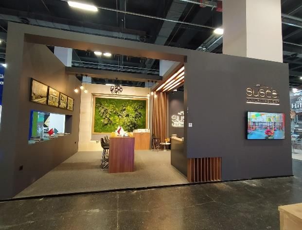 Reception counter, tables and a decorative wall within an exhibition stand with wood detailing